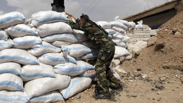 A Free Syrian Army fighter stands behind a pile of sandbags in Raqqa province, east Syria, on May 6, 2013. (REUTERS/Hamid Khatib)