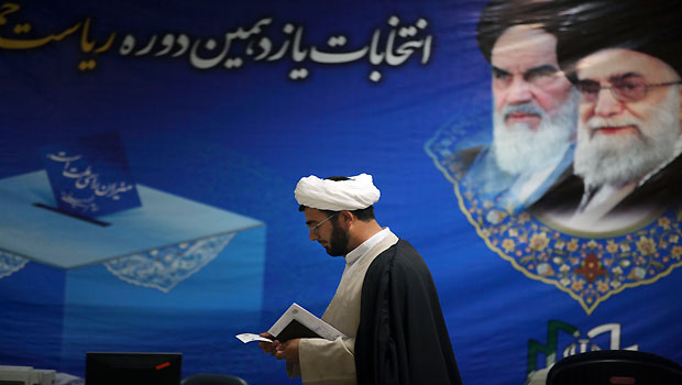 An Iranian cleric arrives at the election headquarters of interior ministry to register his candidacy for the upcoming presidential election, under portraits of the late revolutionary founder Ayatollah Khomeini, left, and supreme leader Ayatollah Ali Khamenei, in Tehran, Iran, Wednesday, May 8, 2013. (AP Photo/Vahid Salemi)