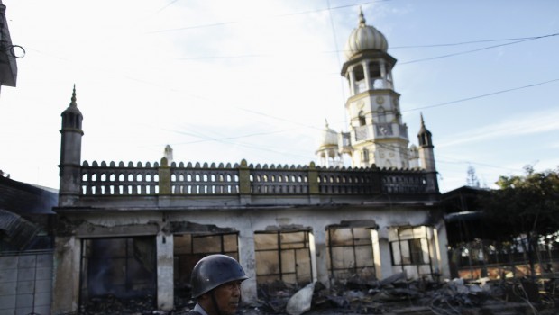 A police officer stands near a mosque which was burnt during a riot between Buddhist and Muslims in Lashio township May 29, 2013. Source: Reuters/Soe Zeya Tun
