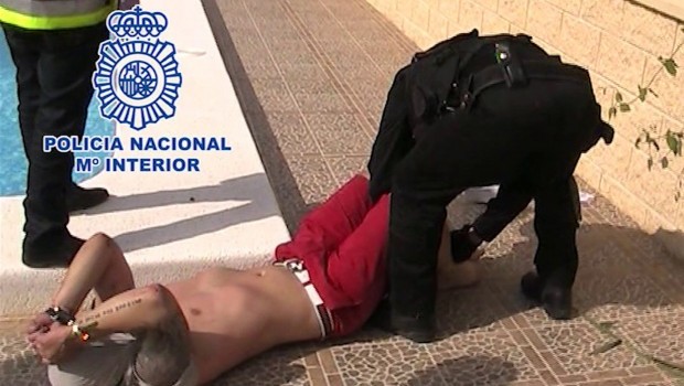 In this photo released Sunday May 12, 2013, by the Spanish National Police and British Serious Organised Crime Agency (SOCA), showing the moment British fugitive Andrew Moran is arrested Friday May 10, 2013, as he relaxed next to the pool of a luxury villa in Alicante, Spain. (AP Photo / Spanish National Police/SOCA)