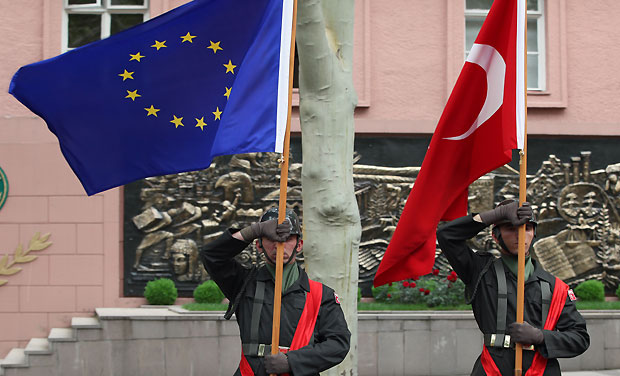Turkish soldiers hold up a Turkish, right, and an European Union flag as European Council President Herman Van Rompuy and Turkish Prime Minister Recep Tayyip Erdogan, both not pictured, inspect a military guard of honour in Ankara, Turkey, Thursday, May 23, 2013. (AP Photo/Burhan Ozbilici)