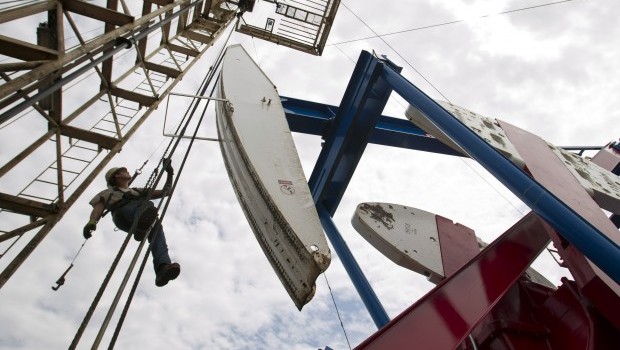 A US worker hangs from an oil derrick in outside of Williston, North Dakota, in this Tuesday, July 26, 2011, file photo. (AP Photo/Gregory Bull)