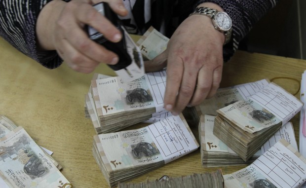 An employee stamps stacks of Syrian pound notes at the Syrian central bank in Damascus April 23, 2013. (Reuters/Khaled Al-Hariri)