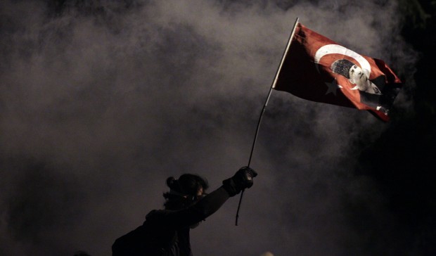 A protester holding a Turkish flag decorated with the image of former leader Mustafa Kemal Ataturk, during clashes near Taksim Square in Istanbul, late Monday, June 3, 2013. (AP Photo/Kostas Tsironis)