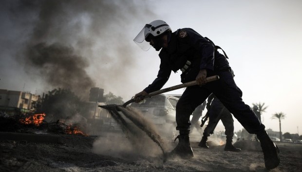 A Bahraini policeman extinguishes tyres burning during clashes with riot police following a protest in solidarity with jailed Bahraini women in the village of Jidhafs, west of Manama, on June 13, 2013. (AFP/Mohammed Al-Shaikh)