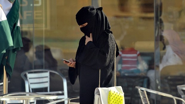 A Saudi woman looks at her mobile as she walks through a coffee shop in the capital Riyadh on June 17, 2013 AFP PHOTO/FAYEZ NURELDINE