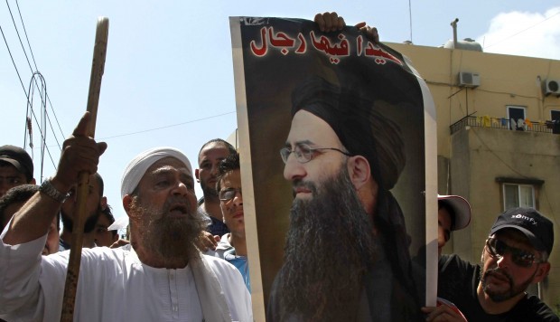 Lebanese protesters hold a poster of hard-line Sunni cleric Sheik Ahmad al-Assir with the Arabic reading, "There are men in Sidon. Anytime you call us we will respond."(AP Photo/Mohammed Zaatari).