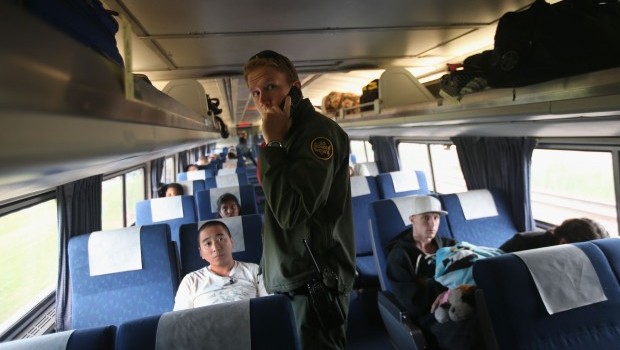 A U.S. Border Patrol agent checks passenger identifications aboard an Amtrak train from Chicago to New York City on June 5, 2013 in Depew, New York. Source: John Moore/Getty Images/AFP