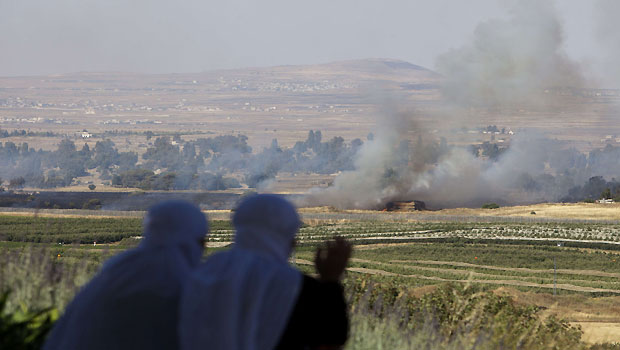 Two Israeli-Druze women look from the Israeli side at the Israel-Syria ceasefire line in the Golan Heights at smoke rising where clashes appeared between Syrian rebels and forces loyal to the regime near the Quneitra crossing on June 6, 2013. (AFP/Ahmad Gharabli) 