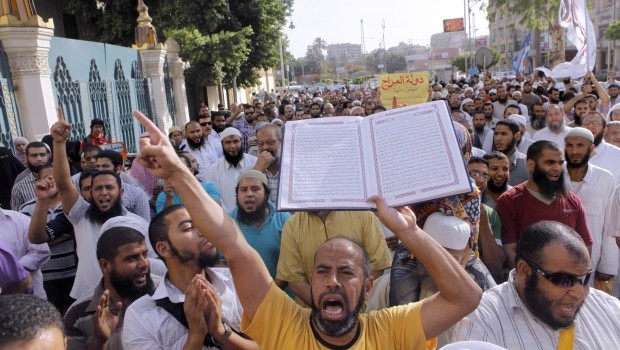 An Egyptian Salafi shouts anti-Mohammed Morsi slogans and holds a copy of the Quran, in support of bearded police officers, who were prevented from carrying out their work in the interior ministry, during a protest in front of the presidential palace in Cairo, Egypt, Saturday, June 1, 2013. Source: AP Photo/Amr Nabil