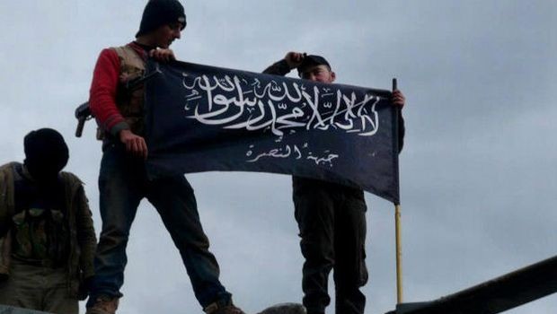 FILE - In this Friday, Jan. 11, 2013 file citizen journalism image provided by Edlib News Network, ENN, which has been authenticated based on its contents and other AP reporting, shows rebels from al-Qaida affiliated Jabhat al-Nusra waving their brigade flag on the top of a Syrian air force helicopter, at Taftanaz air base that was captured by the rebels, in Idlib province, northern Syria. (AP Photo/Edlib News Network ENN, File)