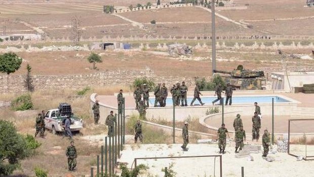 Forces loyal to Syria's President Bashar al-Assad stand near empty swimming pools during what they said a military operation against rebels in al-Mansoura area in Aleppo countryside, June 3, 2013. (REUTERS/George Ourfalian)