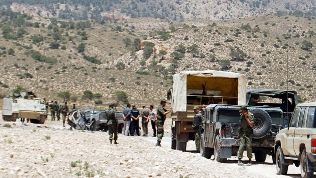Tunisian army stand guard near a demolished vehicle following a roadside bomb in the mountainous border region near Algeria where security forces have been hunting Al-Qaeda linked jihadists, on June 6, 2013. Source: AFP Photo/Abderrazek Khilfi