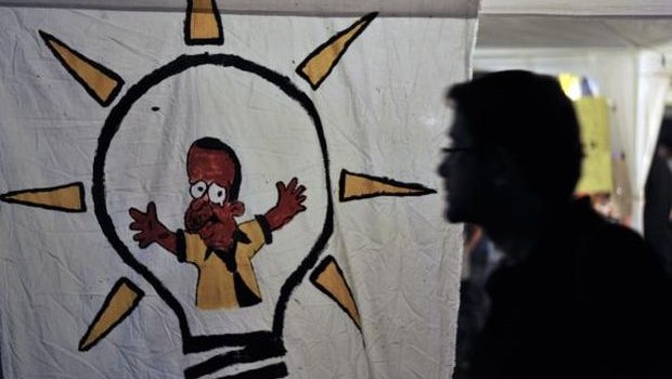 A man walks before a graffiti sign of the Justice and Development Party while protestors dance in a tent at Gundogdu square on June 8, 2013. (AFP PHOTO/OZAN KOSE)