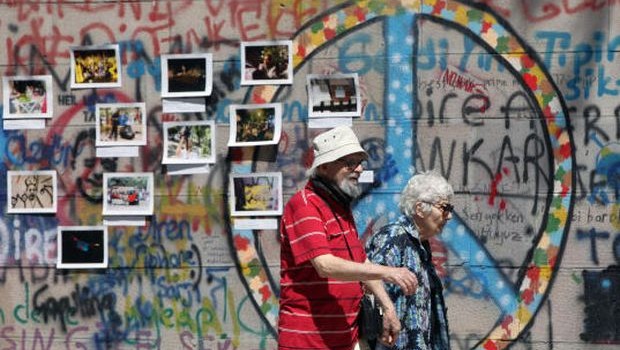 A couple walk past by photographs and graffiti painted by protesters in Kugulu Park in Ankara, Turkey, Wednesday, June 26, 2013. (AP Photo/Burhan Ozbilici)