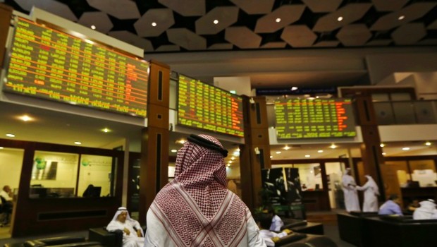 An investor looks up at screens displaying stock information at the Dubai Financial Market on June 17, 2013 (REUTERS/Jumana El Heloueh)