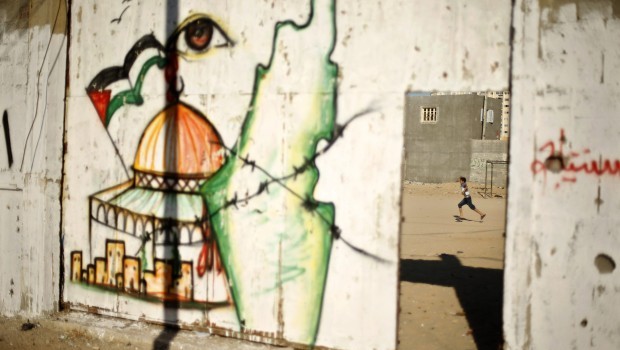 A Palestinian boy plays soccer as a mural depicts the Dome of the Rock and a map of British Mandate Palestine, on the gate of al-Sadaka club in Gaza City June 23, 2013. (REUTERS/Mohammed Salem)