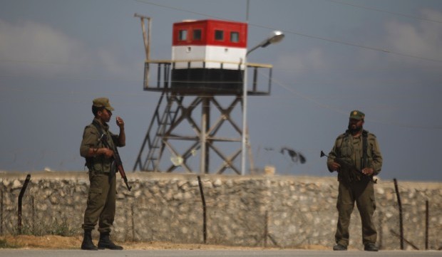 Palestinian Hamas security guards stand near an Egyptian watch tower on the border with Egypt in Rafah, southern Gaza Strip, Friday, July 5, 2013. (AP /Hatem Moussa)