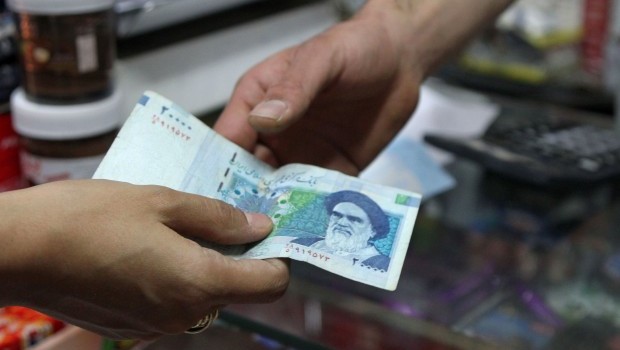 A picture taken on September 30, 2012 shows an Iranian woman paying with a 20000 rial banknote, bearing a portrait of Iran's late founder of Islamic Republic Ayatollah Ruhollah Khomeini, to a grocer in the Iranian capital Tehran. Irans central bank on July 6, 2013 drastically devalued the national currency's fixed subsidized rate against the dollar, as the Islamic republic struggles to shore up its faltering economy (AFP PHOTO/ATTA KENARE)