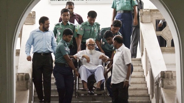 In this photograph taken on May 13, 2012, Ghulam Azam (C), former head of the opposition Jamaat-e-Islami party, is assisted by security personnel as he emerges from the Bangladesh International Crimes Tribunal in Dhaka. A special Bangladesh court on July 13, 2013, found top Islamist, Azam, guilty of masterminding atrocities during the 1971 war of independence against Pakistan (AFP PHOTO/STR/ FILES)