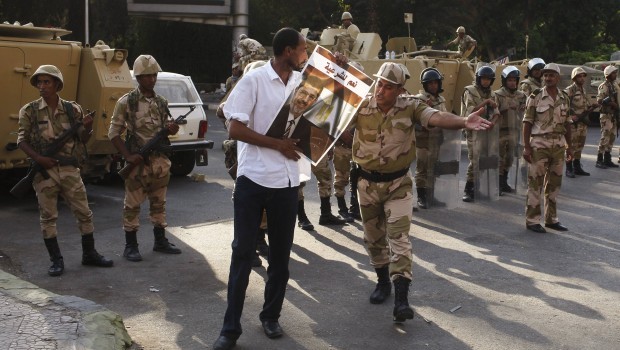 File photo of a soldier asking a supporter of overthrown President Mursi to take his protest to the sidewalk as they stand guard in Giza. (Reuters Photos.)