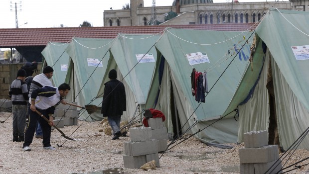 In this picture taken on January 7, 2013, Syrian refugee men stop water from entering their tents, at a temporary refugee camp in the eastern Lebanese town of Marj near the border with Syria, Lebanon. (AP Photo/Hussein Malla.)