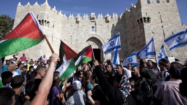  In this May 8, 2013 file photo Israelis and Palestinians wave flags as Israelis march celebrating Jerusalem Day outside Damascus Gate in Jerusalem's old city (AP Photo/Sebastian Scheiner, File)