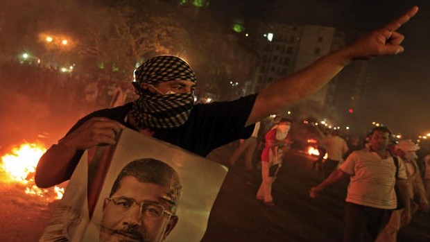 A Supporter of ousted President Mohammed Morsi holds a poster of him during clashes in downtown Cairo, Egypt, Monday, July 15, 2013. (AP Photo/Khalil Hamra)
