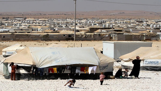 Syrian refugees stand near their tent at Zaatari camp near the Syrian border, near Mafraq, Jordan, Friday, July 26, 2013. (AP Photo/Raad Adayleh)