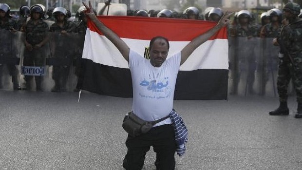 A member of the "Tamarod - Rebel!" petition drive against Mursi, gestures with an Egyptian flag in front of army soldiers standing guard in front of protesters who are against Egyptian President Mohamed Mursi, near the Republican Guard headquarters in Cairo July 3, 2013. REUTERS/Amr Abdallah Dalsh