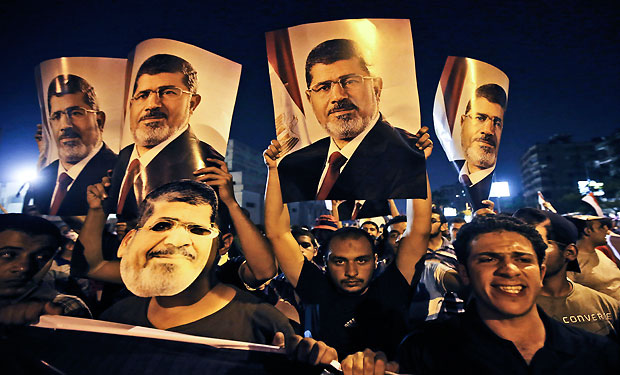 In this Wednesday, July 10, 2013 photo, supporters of ousted Egypt's President Mohammed Morsi, hold posters of him as they protest during the Islamic month of Ramadan, in Nasr City, Cairo, Egypt.  (AP Photo/Hussein Malla)