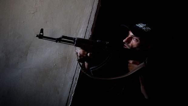 A rebel fighter points his gun towards pro-government forces' positions during clashes in the Salaheddine district of the northern Syrian city of Aleppo, on July 9, 2013. (AFP/JM Lopez)