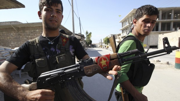 A Kurdish fighter from the Popular Protection Units (YPG) shows his weapon decorated with his party's flag, as a fellow fighter looks on in Aleppo's Sheikh Maqsoud neighbourhood, June 7, 2013. (REUTERS/Muzaffar Salman.) 