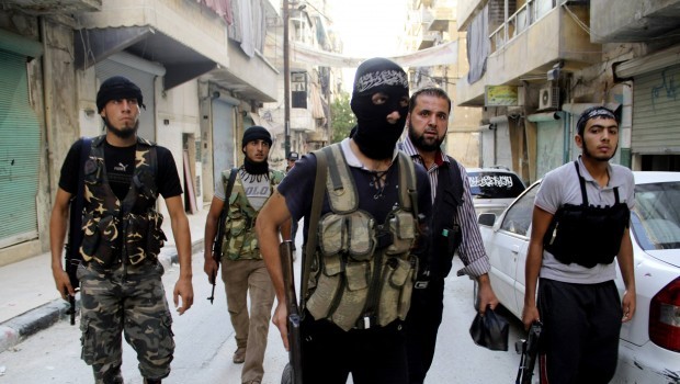 Free Syrian Army fighters carry their weapons as they walk along a street prior to an offensive against forces loyal to Syria's President Bashar al-Assad, in Aleppo's Salaheddine neighborhood, July 6, 2013. Picture taken July 6, 2013. (REUTERS/Malek Alshemali.)