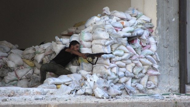 A Free Syrian Army fighter aims his weapon as he takes up a position behind sandbags in the al-Khalidiya neighborhood of Aleppo, August 4, 2013. (REUTERS/Aref Hretani)