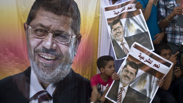 Supporters of deposed Egyptian president Mohamed Morsi (portrait) watch a football match between the two main Cairo protest camps by members of the Muslim Brotherhood and backers of the ousted Islamist leader set up at the Nahda and Rabaa al-Adawiya squares, on August 11, 2013 in Cairo's al-Nahda square. (AFP PHOTO/ KHALED DESOUKI.)