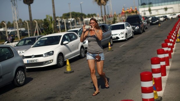 A woman takes a photo with her mobile phone as drivers wait in line to enter to Spain at its border with the British territory of Gibraltar in Gibraltar, south of Spain August 12, 2013. Britain warned Spain on Monday it might take legal action to try to force Madrid to abandon tighter controls at the border with the contested British overseas territory of Gibraltar in what it called an "unprecedented" step against a European ally (REUTERS/Jon Nazca) 