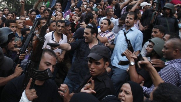 A plain clothes policeman (C) points his gun as security forces escort Muslim Brotherhood members through supporters of the interim government installed by the army from the Al-Fath mosque on Ramses Square in Cairo August 17, 2013. Supporters of deposed President Mohamed Mursi fought a gun battle with security forces in a Cairo mosque on Saturday, while Egypt's army-backed government, facing deepening chaos, considered banning his Muslim Brotherhood group. (REUTERS/Amr Abdallah Dalsh)
