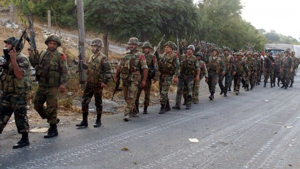 A handout picture released by the Syrian Arab News Agency (SANA) on August 8, 2013 shows Syrian army soldiers walking on a road during an alleged pursuit of opposition fighters in the Latakia province, western Syria. (AFP Photo/SANA)