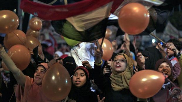 Supporters of Egypt's ousted President Mohammed Morsi hold balloons and national flags as they celebrate the first day of the Eid al-Fitr feast, marking the end of the Muslim holy fasting month of Ramadan that is traditionally celebrated with special cookies, presents and new clothes outside Rabaah al-Adawiya mosque, where protesters have installed a camp and hold daily rallies at Nasr City in Cairo, Egypt, Wednesday, Aug. 8, 2013. (AP Photo/Khalil Hamra)