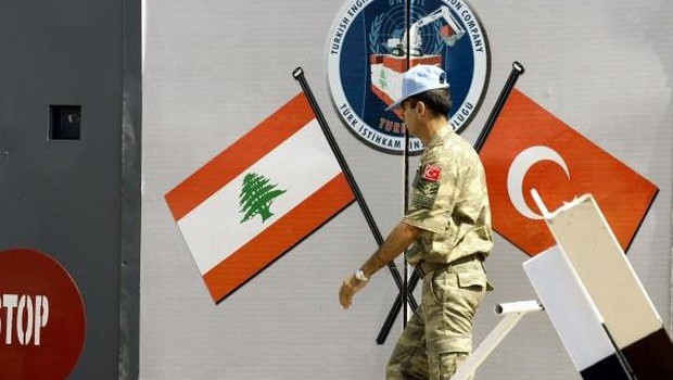 A member of the Turkish engineering contingent in the United Nations Interim Force in Lebanon (UNIFIL) walks past a wall depicting flags at the entrance of the Turkish engineering construction company's base on August 10, 2013 . (AFP PHOTO/MAHMOUD ZAYYAT)
