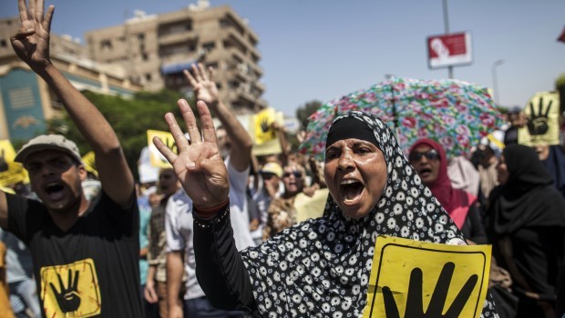 Supporters of ousted Egyptian president Mohamed Mursi raise up posters with the four-finger symbol during a demonstration against the military backed government in the Egyptian capital, Cairo, on September 13, 2013.  (AFP PHOTO / MAHMOUD KHALED)