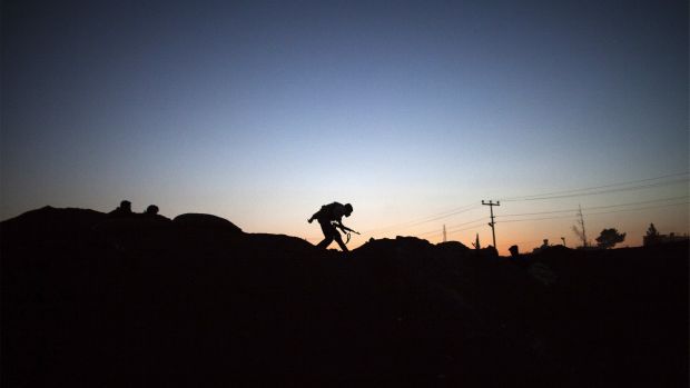 The silhouette of an armed fighter with the Kurdish Peoples' Protection Units (YPG) is seen as he runs to take position along the front line on October 16, 2013, in the Syrian town of Ras Al-Ain, close to the Turkish border. (AFP PHOTO/STR)