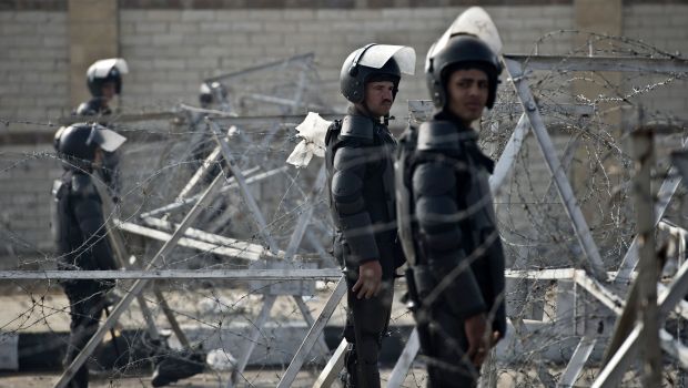 Egyptian riot policemen stand guard behind barbed wire outside the Police Academy where a hearing in the espionage trial of Egypt's ousted Islamist president Mohamed Mursi is expected to open on February 16, 2014 in Cairo. (AFP Photo/ Khaled Desouki)
