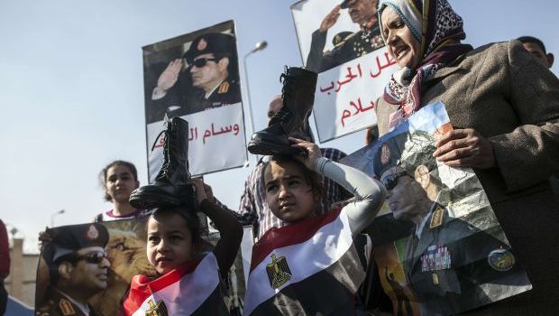 Supporters of Egypt's army chief, Field Marshal Abdel-Fattah El-Sisi, hold military boots on their heads in a sign of support for military rule on January 28, 2014. (AFP PHOTO/MAHMUD KHALED)