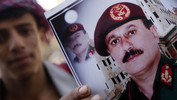 A vendor poses with images of former President Ali Abdullah Saleh (bottom) in Sana'a on March 1, 2014. (REUTERS/Mohamed al-Sayaghi)