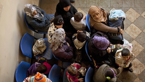 In this Wednesday, December 18, 2013, file photo, Syrian women wait with their children at the UN refugee agency's registration center in Zahleh, in Lebanon's Bekaa Valley.  (AP Photo/Maya Alleruzzo, File)