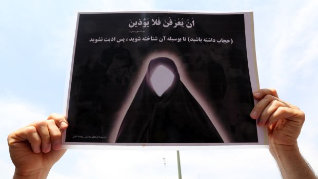 A supporter of Iranian religious hardliners raises up a poster reading in Persian " Please keep your Islamic dress code to be recognised as a real Muslim woman" as she takes part in a demonstration after the weekly Friday prayer in Tehran on May 16, 2014. (AFP Photo)