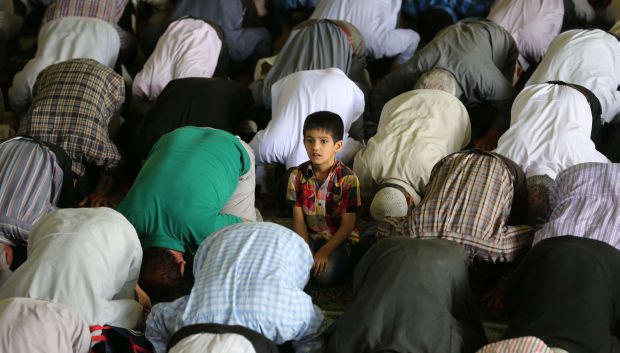 An Iranian boy stands among Shi'ite Muslim worshippers attending the weekly Friday prayer on May 16, 2014, at the university of the Iranian capital, Tehran. (AFP PHOTO/ATTA KENARE)