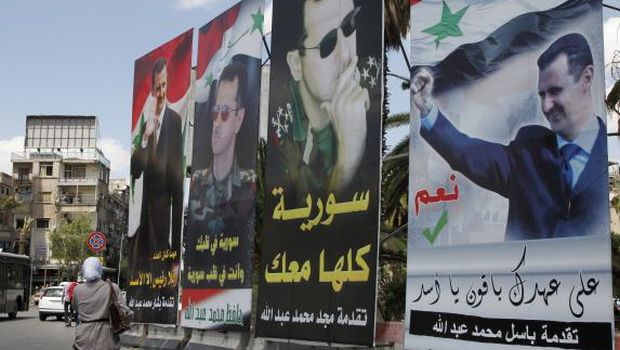 A woman walks past election posters of Syria's President Bashar Al-Assad along a street in Damascus on June 2, 2014. (Reuters/Khaled Al-Hariri)